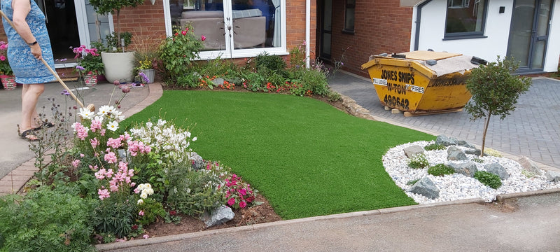 A black Labrador laying on artificial grass