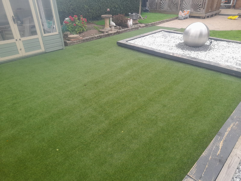 artificial grass with silver water feature on raised gravel bed