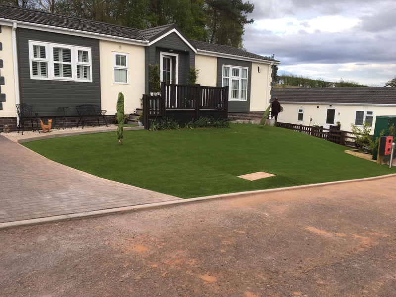 Artificial lawn with static caravan lodge with porch in the background