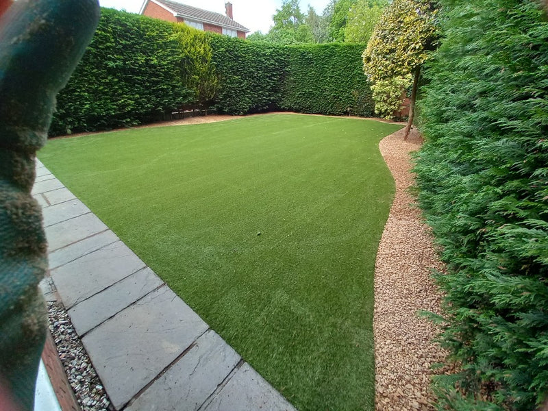 large lawn with gravel borders and trees surrounding the perimeter