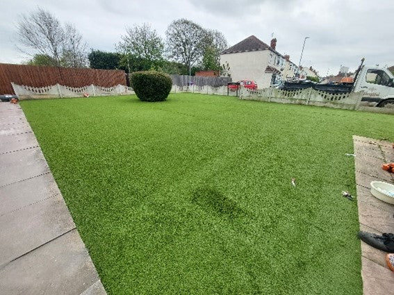 large lawn with gravel borders and tree in the corner